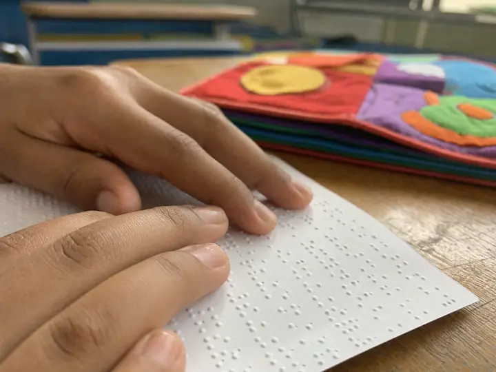 As pontas dos dedos de uma criança lendo uma página em braile